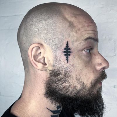 Get a unique and detailed blackwork symbol tattoo done by the talented artist Hellie. Perfect for those looking for a bold and striking design.