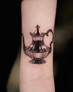 Experience the brilliance of Gloria Gu's black and gray micro realism tattoo featuring a shiny chrome pot motif.