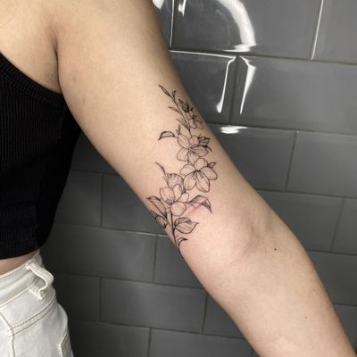 Adorn your skin with a breathtaking floral fine line tattoo by the talented artist Tas Kal. Bring beauty and elegance to your body with this stunning design.