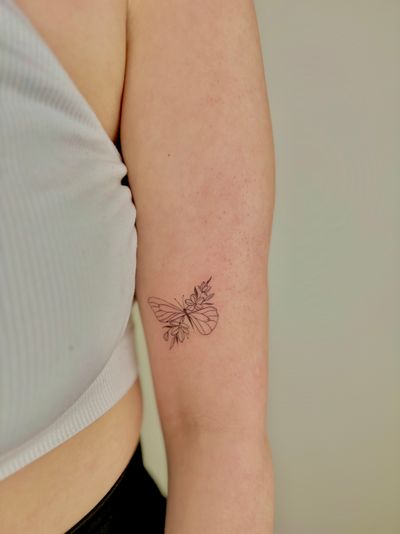 Get inked with a delicate butterfly and flower design by Ruth Hall, expert in fine line tattoos. Perfect for a touch of elegance!