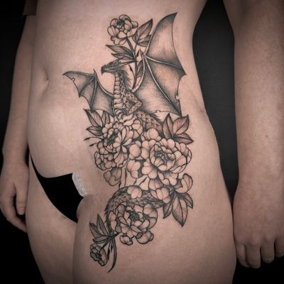 Get mesmerized by the intricate details of this black and gray illustrative tattoo featuring a dragon and flower design, expertly crafted by Jenny Dubet.