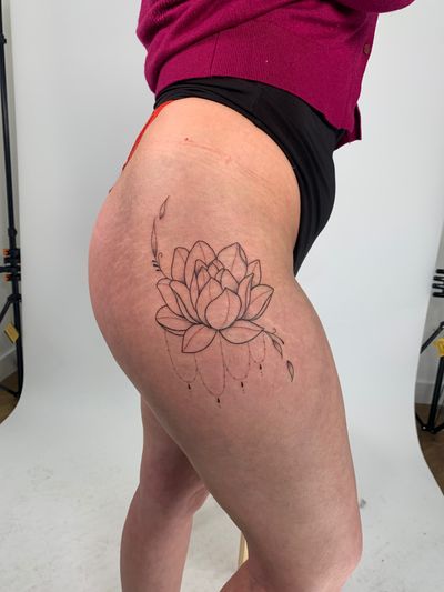 Beautiful fine line tattoo featuring a delicate lotus flower design by talented artist Chloe Hartland.