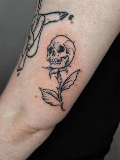 Get a stunning illustrative tattoo featuring a beautiful flower and skull design by Jonathan Glick.