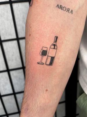 Raise a toast to this stunning tattoo featuring a wine bottle, glass, and grapes by Jonathan Glick.