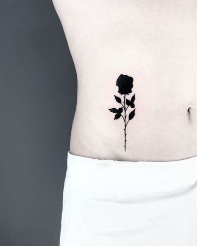 A stunning fullblack rose tattoo by Malvina Maria Wisniewska, showcasing intricate blackwork style with bold lines and shading.
