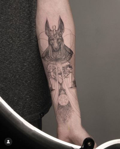 This fine line black and gray tattoo features a unique blend of Anubis, tree, roots, and scale motifs, executed with precision and elegance by talented artist Kayla.