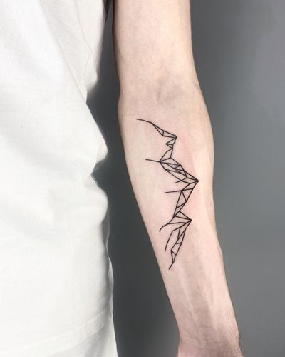 Discover the beauty of fine lines and geometric shapes in this stunning mountain tattoo by Malvina Maria Wisniewska.