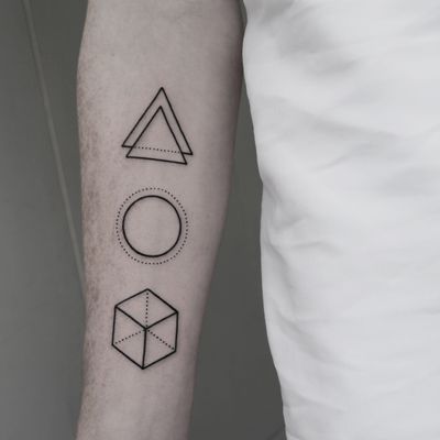 Experience the intricate beauty of a geometric tattoo featuring a circle, triangle, and cube, designed by Malvina Maria Wisniewska.