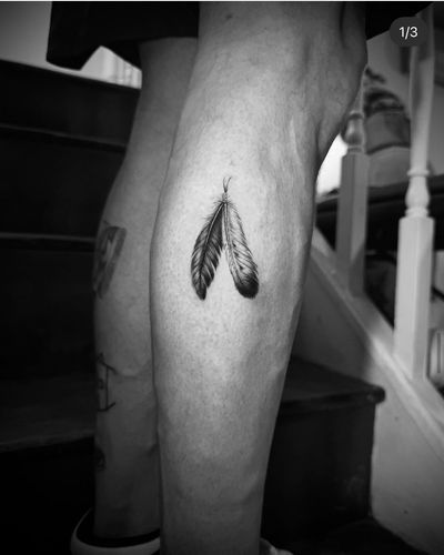Discover the intricate details of this black and gray feather tattoo by Georgina. Perfect for those who appreciate micro realism artistry.