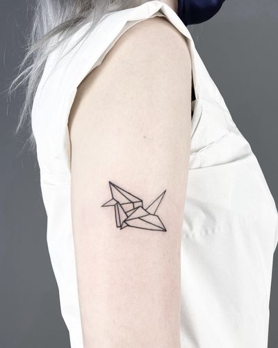Experience the delicate beauty of origami with this fine line geometric tattoo of a crane by the talented artist Malvina Maria Wisniewska.