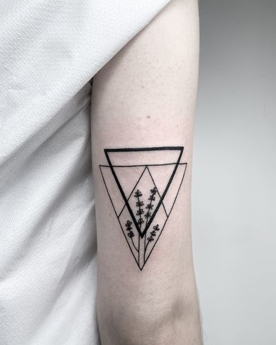 Unique blackwork and fine line tattoo by Malvina Maria Wisniewska featuring a stunning floral motif within a geometric triangle design.
