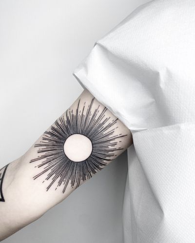 Experience the beauty of a blackwork fine line sun tattoo by Malvina Maria Wisniewska. Let the sun bring serenity to your skin.