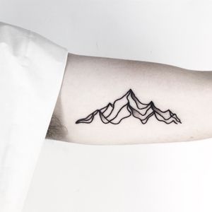 Explore the beauty of nature with this striking blackwork tattoo featuring a geometric mountain design by Malvina Maria Wisniewska.