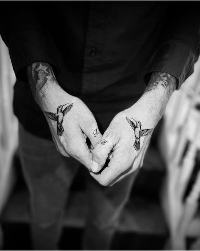Experience the intricate beauty of a black and gray micro realism hummingbird tattoo, expertly created by artist Georgina.