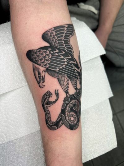 Get inked with a stunning traditional tattoo featuring a snake and eagle, expertly done by Ryan Goodrum.
