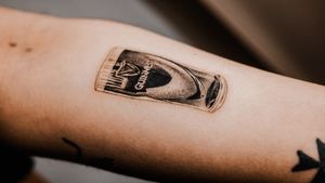 Incredible micro realism tattoo by Gabriele Edu featuring a glass of Guinness beer