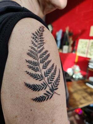 Get a stunning blackwork tattoo of a delicate fern branch, designed by the talented artist Mary Shalla.