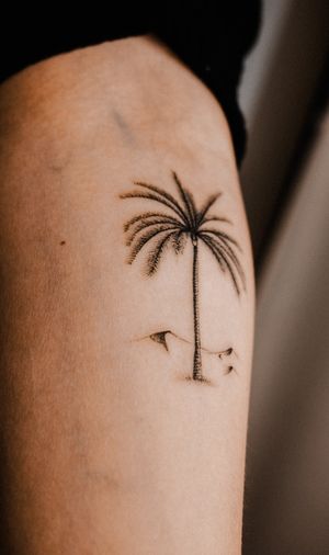 Get lost in this stunning black and gray tattoo by Gabriele Edu featuring a serene beach scene with palm tree, coconut tree, and dunes.