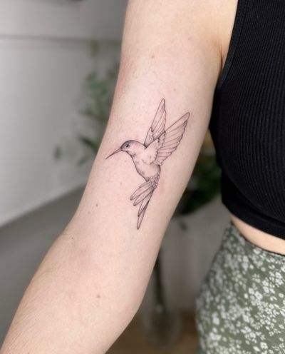 Fine line, illustrative tattoo of a hummingbird in motion by Lucas Scardua. Delicate and elegant design.