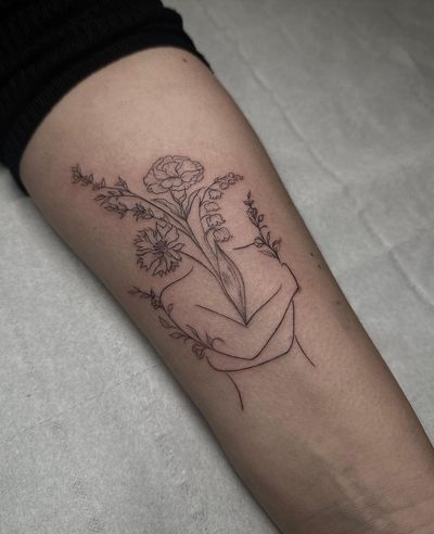 Delicate fine line tattoo by Maddie showcasing a woman embracing self love surrounded by intricate floral elements.
