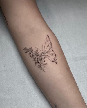 Stunning illustrative tattoo by Maddie, featuring a beautiful butterfly and flower design, exquisitely detailed and elegant.