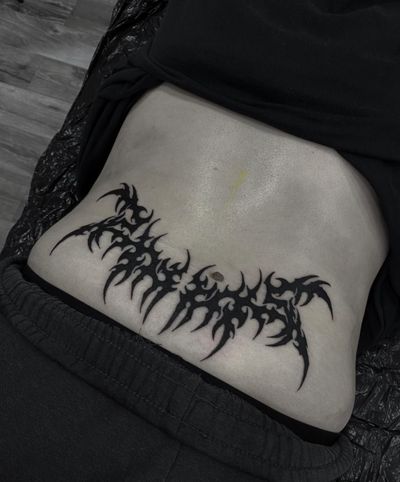 Sophia Hayes' intricate blackwork tribal tattoo blends cyber sigilism with traditional tramp stamp motifs.