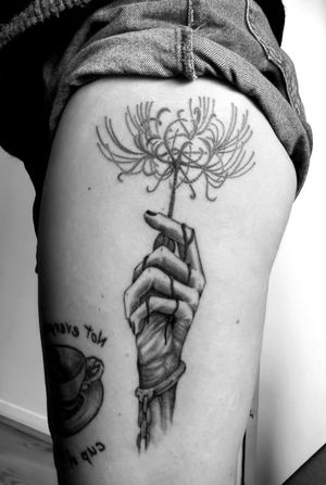 Get mesmerized with this stunning black and gray illustrative tattoo of a hand holding a spider lily, by Gabriele Lacerenza.