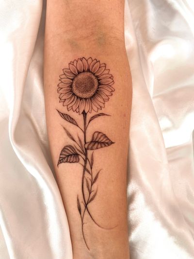 This black and gray illustrative tattoo of a sunflower was beautifully designed by Gabriela, capturing the elegance and beauty of nature.