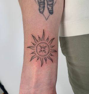 Experience the radiant beauty of the sun in this fine-line, illustrative tattoo by Chloe Hartland. Dive into a world of serenity and warmth with this stunning design.