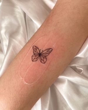 Experience the delicate beauty of a fine line butterfly tattoo designed by Gabriela, featuring intricate geometric patterns.