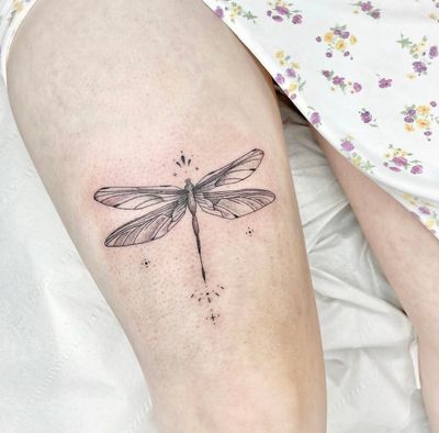 Experience the delicate beauty of a fine line illustrative dragonfly tattoo, expertly executed by Beyza Taser.