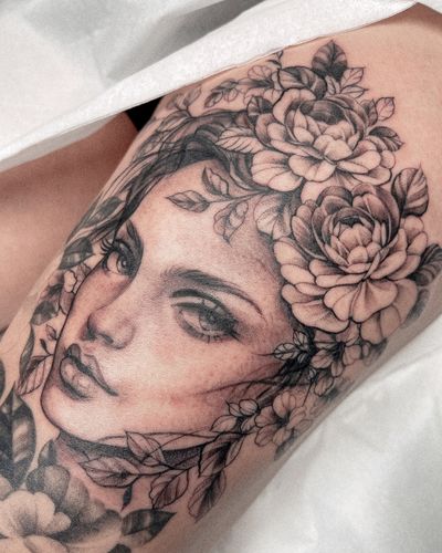 A stunning black and gray tattoo featuring a beautiful lady surrounded by intricate floral elements, expertly done by Beyza Taser.