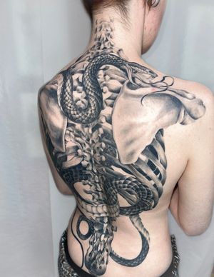 Stunning black and gray tattoo of a snake intertwined with ribcage bones, expertly done by Beyza Taser.