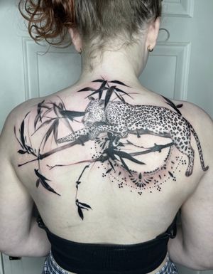 Blackwork illustrative tattoo of a leopard or jaguar with a brush and branch, beautifully done by Beyza Taser.