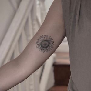 Get a beautifully detailed black and gray illustrative sunflower tattoo by the talented artist Monike.