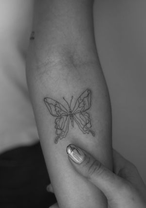 Discover the beauty of simplicity with this fine line illustrative tattoo by Meg, featuring a stunning single line butterfly motif.