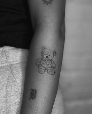 Get inked with a delicate illustrative teddy bear tattoo designed by the talented artist Meg. Perfect for animal lovers!
