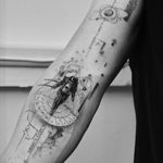 Explore the cosmos with this intricate black and gray, fine line tattoo by Victoria featuring a planet, astronaut, and coordinates. Perfect for space enthusiasts!