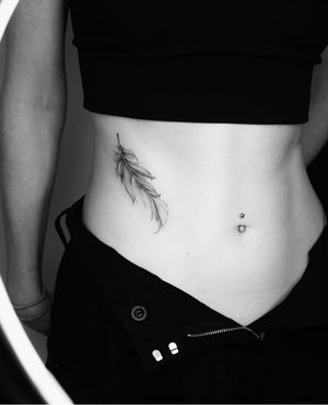 Exquisite black and gray tattoo of a feather, created with intricate details by artist Victoria.