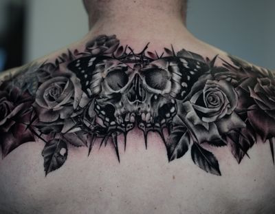 Dark black and grey realism skull butterfly and roses. Spanning across the shoulder blades. 