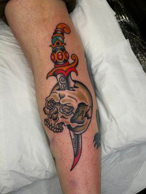 Get inked by the legendary artist Barney Coles with this classic traditional design featuring a skull and dagger motif.