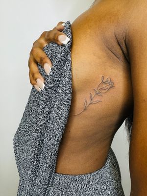 Elegant hand-poked single line illustrative rose tattoo, perfect for dark skin tones. Book with jadeshaw_tattoos now!