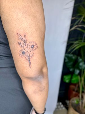 Exquisite illustrative design by jadeshaw_tattoos, featuring a delicate bouquet of flowers in fine line style.