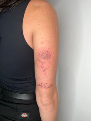 Experience the beauty of fine line art with this stunning floral design by Emma InkBaby. Perfect for those looking for a subtle and elegant tattoo.