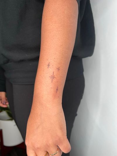 Adorn your skin with a delicate fine line star tattoo created by the talented artist Emma InkBaby.