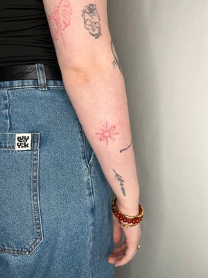 Illustrative tattoo of a red star by Emma InkBaby, featuring intricate fine line work.