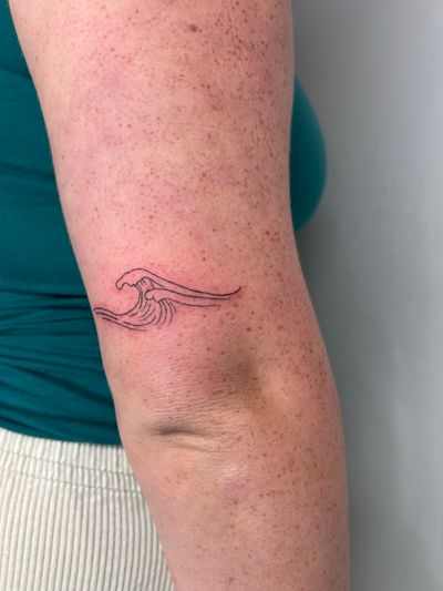 Experience the calming beauty of waves with this delicate fine line tattoo by Emma InkBaby.
