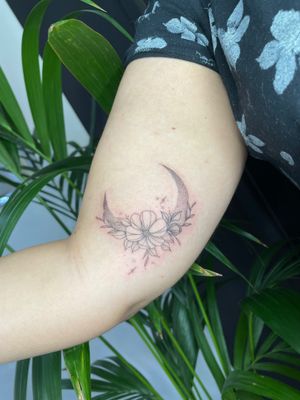 Experience the beauty of dotwork and fine line techniques in this illustrative tattoo by Emma InkBaby, featuring a moon and flower motif.