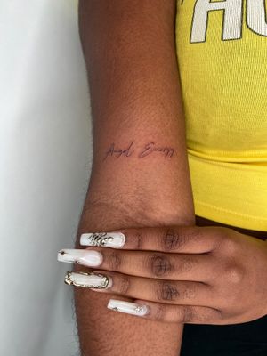 Elegantly designed fine line tattoo with small lettering, created by the talented artist Emma InkBaby.