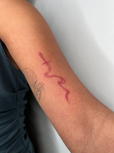 Get a bold illustrative sword tattoo in striking red ink, designed by the talented artist Emma InkBaby.